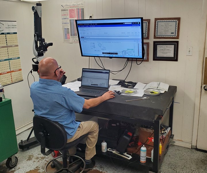 Man sits at a computer next to a laser scanning arm